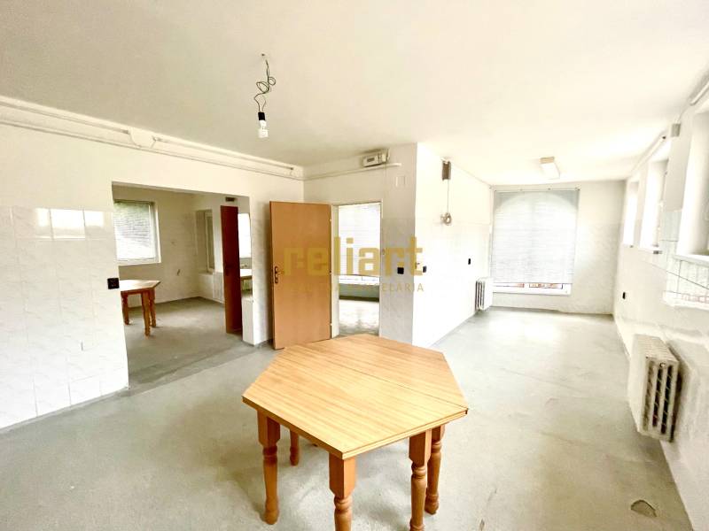 Tágas szoba faasztalokkal és radiátorokkal egy családi házban.