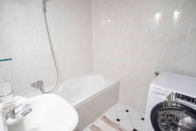 Fürdőszoba zuhanyzó káddal, mosdóval és mosógéppel egy 4 szobás lakásban.