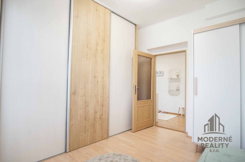 4 szobás lakás belső tere fa dekor padlóval és tolóajtós szekrényekkel.