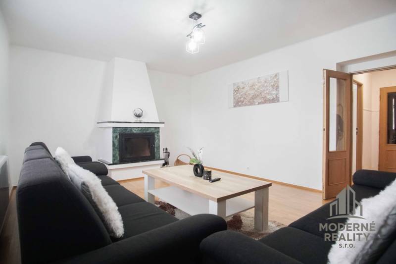 Nappali egy 4 szobás lakásban kandallóval és fa dekorációjú padlóval.