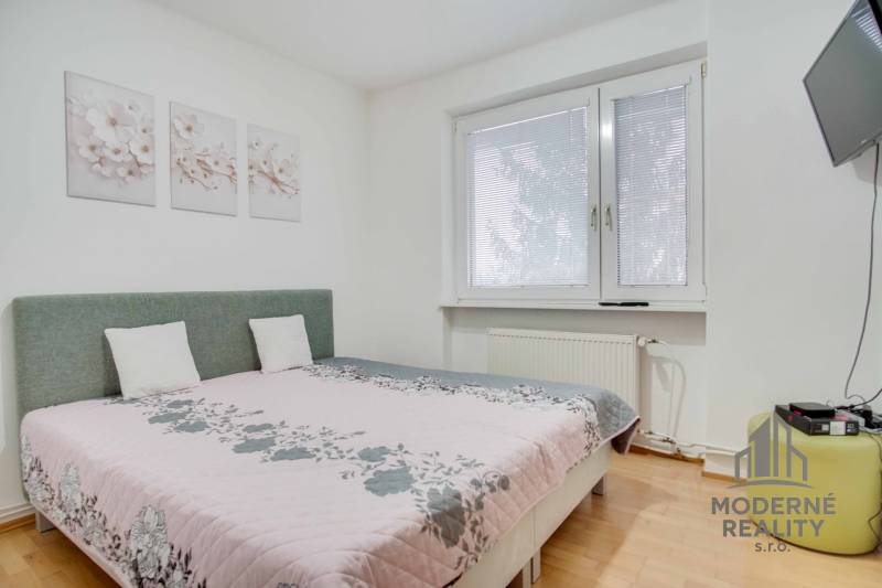 Hálószoba egy 4 szobás lakásban virágos dekorációkkal és falra szerelt televízióval.