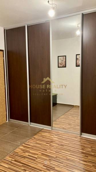 Tolóajtós és tükrös szekrény egy háromszobás lakásban, fa dekoros padlóval.