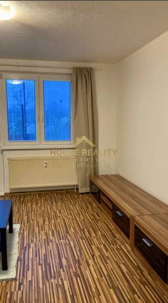 Nappali egy háromszobás lakásban, fa dekorációjú padlóval és kilátással egy nagy ablakon keresztül.