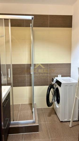 Fürdőszoba zuhanyzóval és mosógéppel egy háromszobás lakásban.