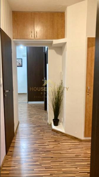 Előszoba egy háromszobás lakásban, fa dekoros padlóval és beépített szekrényekkel.