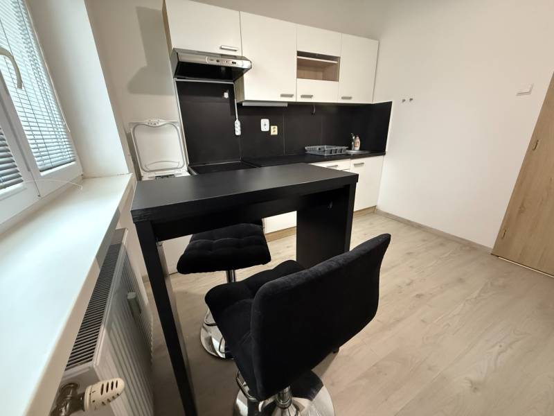 Konyha ülőhellyel és fa dekoros padlóval egy egyszobás lakásban.