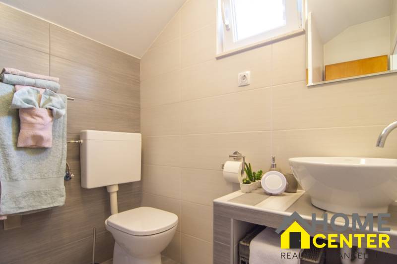 Fürdőszoba a nyaraló apartmanban zuhanyzóval, mosdóval, WC-vel és apró dekorációkkal.