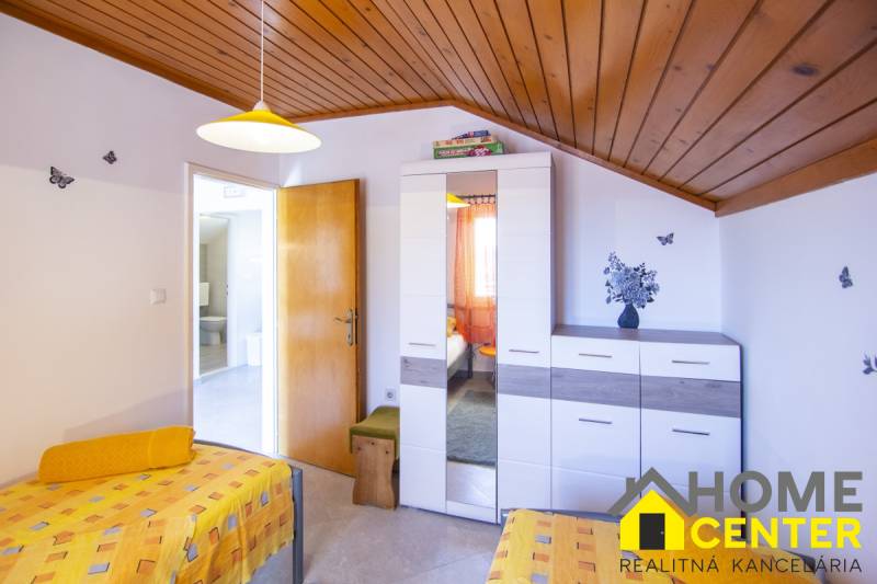 Hálószoba a nyaraló apartmanban színes ágyneművel, szekrénnyel és faldekorációkkal.