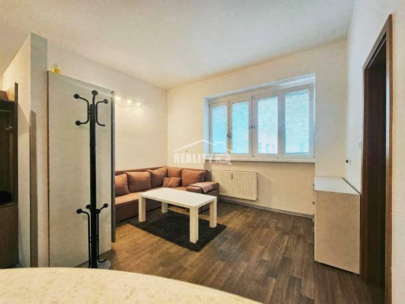 Garzonlakás kanapéval, asztallal és fa dekorációjú padlóval.