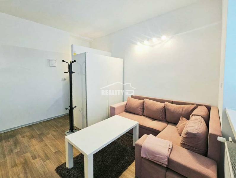 Garzonlakás sarokkanapéval, fehér asztallal és fa dekorációjú padlóval.