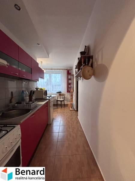 Konyha egy kétszobás lakásban, fa dekoros padlóval, háttérben étkező sarokkal.