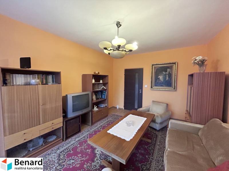 Nappali retro bútorokkal egy kétszobás lakásban, fa dekorációjú padlóval, szőnyegekkel.