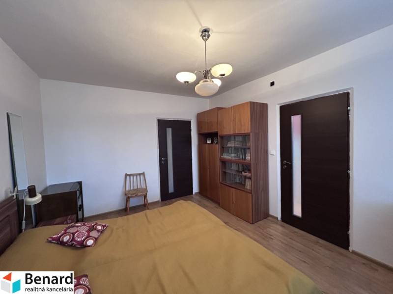 Hálószoba egy kétszobás lakásban ággyal, szekrénnyel és fa dekorációjú padlóval.