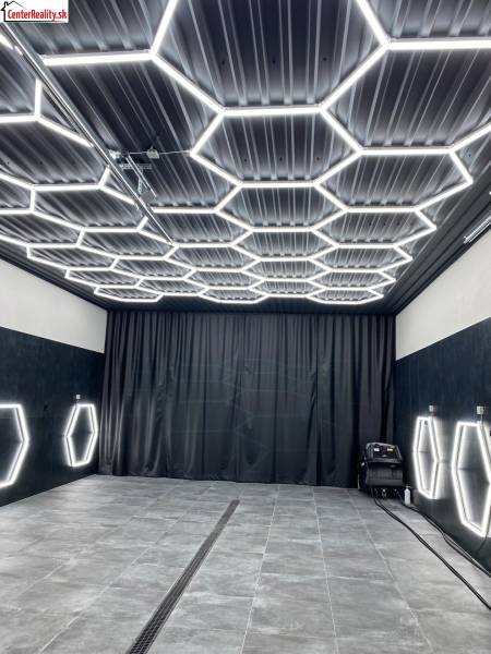 Sötét dekorral rendelkező üzlethelyiség hatszögletű LED világítással a mennyezeten és a falakon.