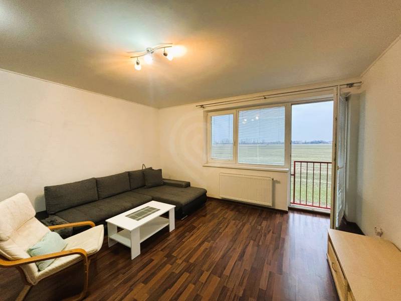 Nappali egy kétszobás lakásban, fa dekor padlóval és kanapéval.