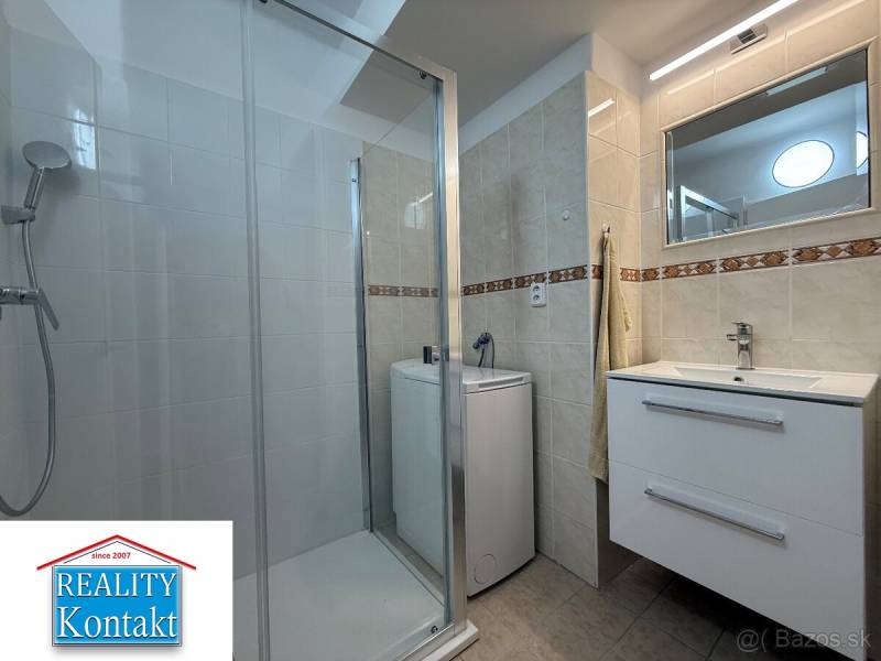 Fürdőszoba egy kétszobás lakásban mosdóval, zuhanyzóval és mosógéppel.