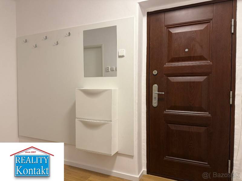 Előszoba egy kétszobás lakásban sötét ajtókkal és fa dekorációjú padlóval.