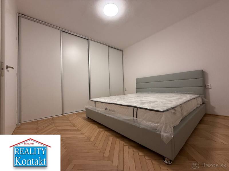 Hálószoba egy kétszobás lakásban, fa mintás padlóval és nagy beépített szekrénnyel.