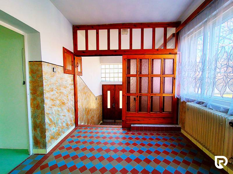 Folyosó egy családi házban színes mintás csempével, faajtókkal és függönyökkel.