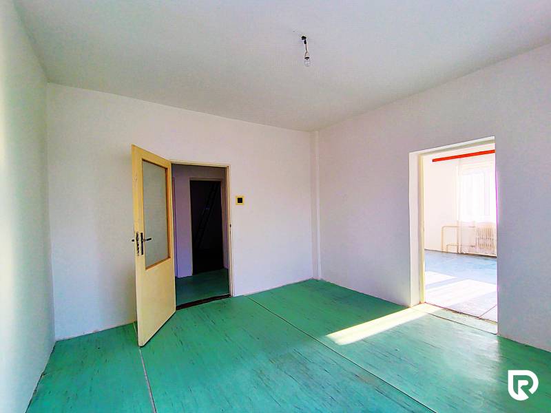 Családi ház belső tere nyitott ajtókkal, fehér falakkal és zöld padlóval.