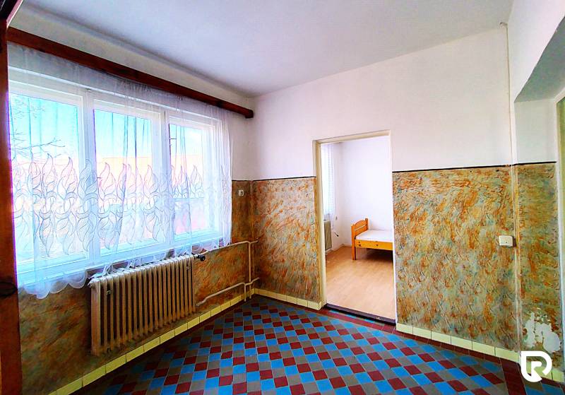 Családi ház belső tere járólappal, radiátorral és függönyös ablakkal.