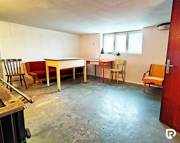 Családi ház pincéje bútorokkal és ablakkal, betonpadló.