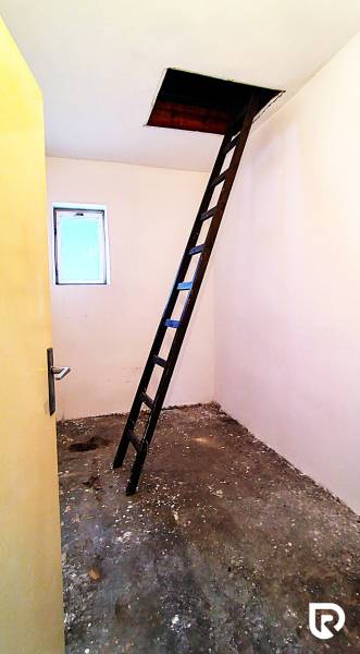Padlás egy családi házban, létrával, amely a mennyezeti nyíláshoz vezet.