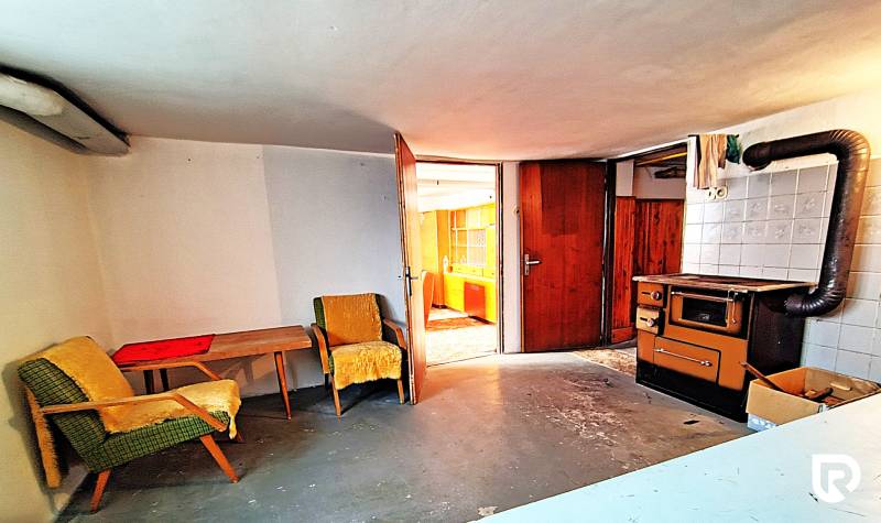 Szoba egy családi házban székekkel, asztallal és régi tűzhellyel.