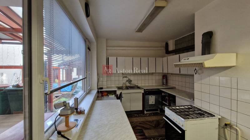 Konyha családi házban háztartási gépekkel, csempékkel és teraszra néző ablakkal.