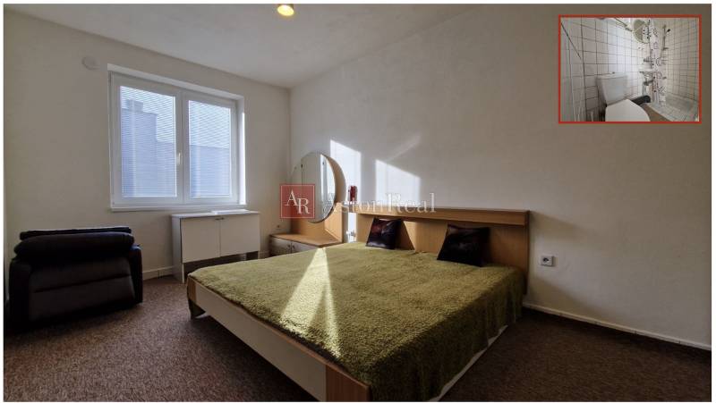 Hálószoba franciaággyal, zöld takaróval, éjjeliszekrénnyel és tükörrel egy családi házban.