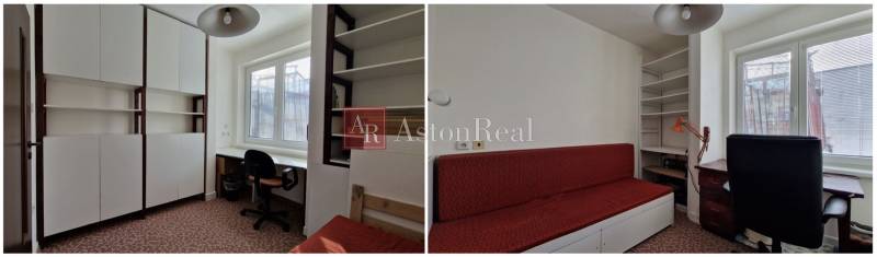 A családi házban fehér szekrények, egy munkasztal és egy piros kanapé van.