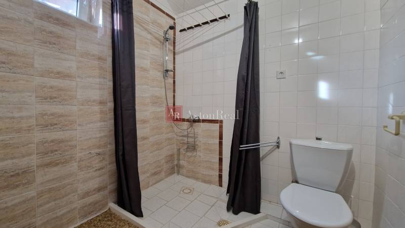 Fürdőszoba egy családi házban egyszerű zuhanyzóval és világos csempékkel.