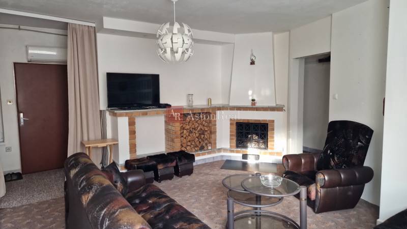 Nappali kandallóval egy családi házban, bőrfotel és dohányzóasztal.