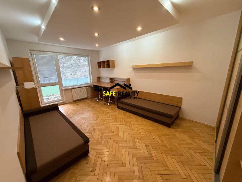 Nappali egy háromszobás lakásban, fa dekoros padlóval és íróasztallal.