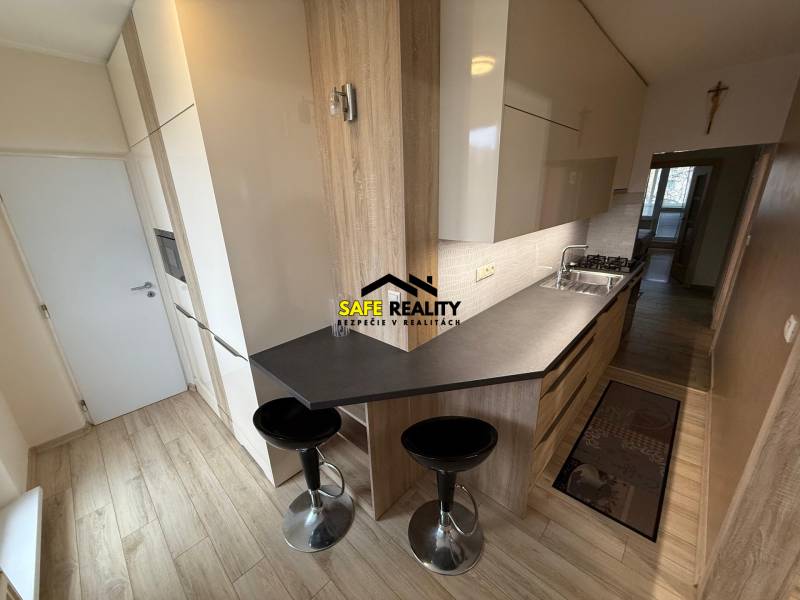 Konyha egy háromszobás lakásban fa dekor padlóval és étkezőpulttal.