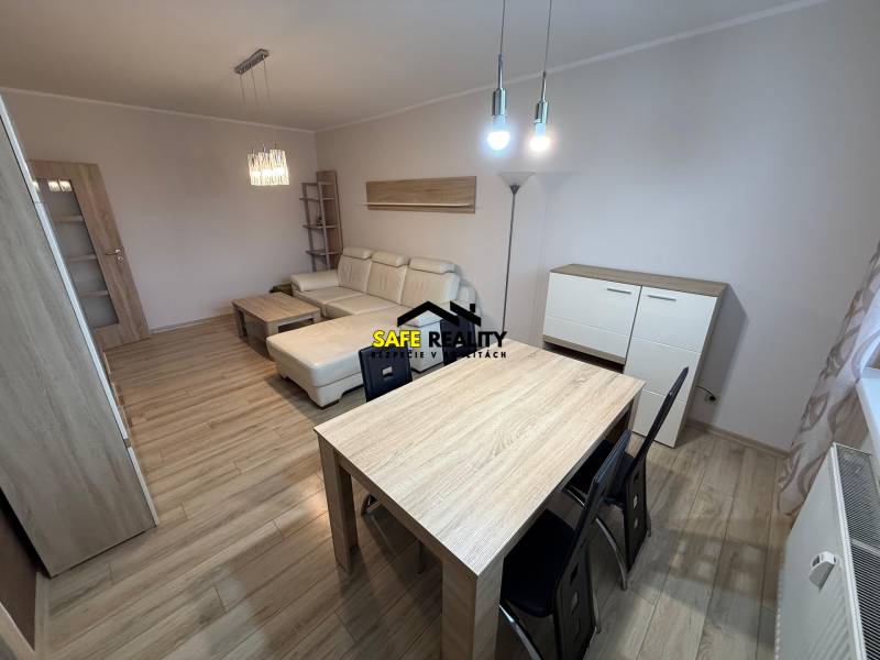 Nappali fa mintázatú padlóval, kanapéval és asztallal egy háromszobás lakásban.