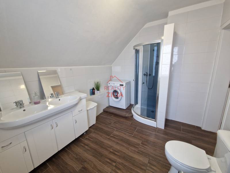 Fürdőszoba családi házban mosdóval, zuhanyzóval és fa dekoros padlóval.