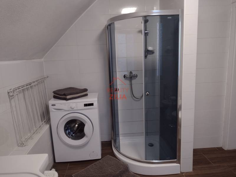 Fürdőszoba családi házban mosógéppel, zuhanyzóval és fa dekorációjú padlóval.