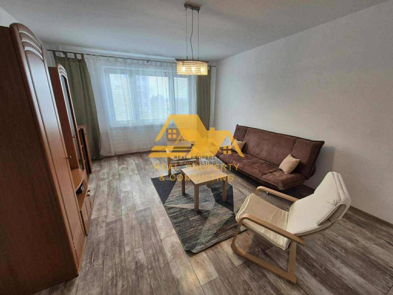 Nappali egy háromszobás lakásban kanapéval, fotellel és fa dekorációjú padlóval.