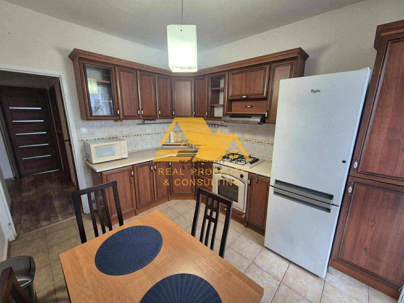 Konyha sötét fa dekorációval, tűzhellyel és hűtőszekrénnyel egy háromszobás lakásban.