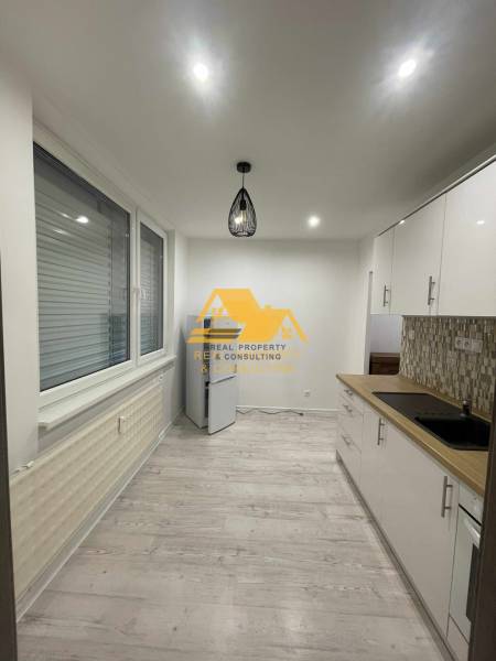 Konyha egy egyszobás lakásban, fa dekorációjú padlóval és modern világítással.