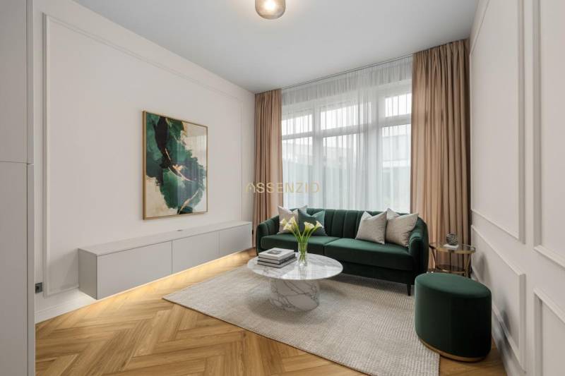 Nappali zöld kanapéval, dekoratív asztallal és fa mintázatú padlóval.