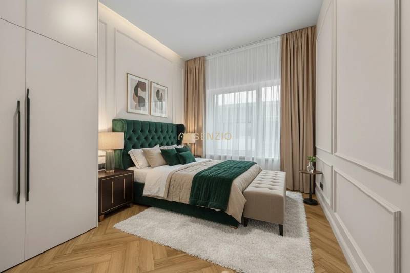 Hálószoba ággyal, éjjeliszekrényekkel, falon lévő képekkel és fa dekoros padlóval.