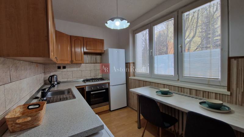 Konyha egy 2 szobás lakásban, fa dekoros padlóval és háztartási gépekkel.