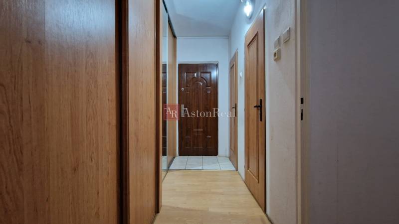 Folyosó egy kétszobás lakásban, fa dekorációval ellátott padlóval és beépített szekrénnyel.