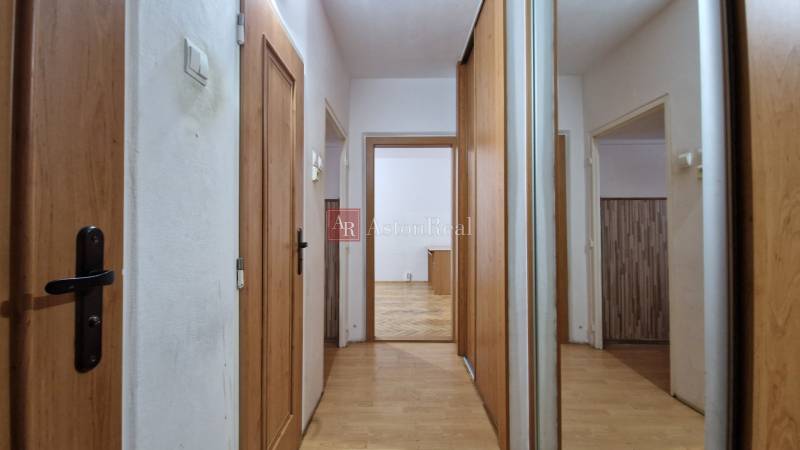 Két szobás lakás folyosója fa dekorációjú ajtókkal és padlóval.