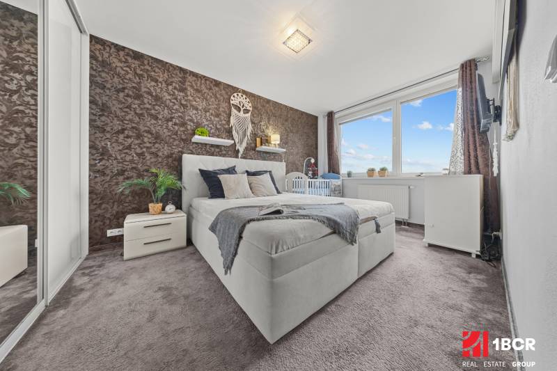 Hálószoba egy kétszobás lakásban franciaággyal, szőnyegpadlóval és dekoratív fallal.