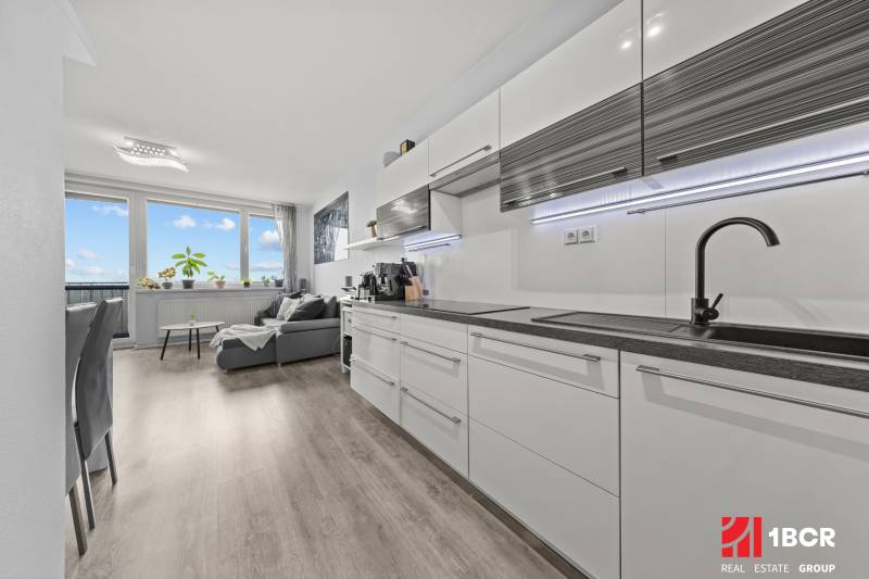 Konyha és nappali egy kétszobás lakásban fa dekoros padlóval.