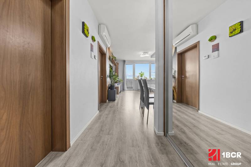 2 szobás lakás belső tere fa dekor padlóval, tükörrel és légkondicionálóval.