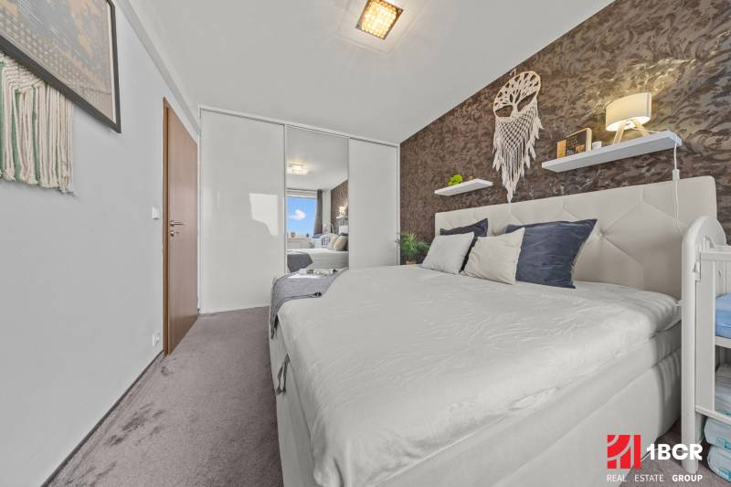 Hálószoba egy kétszobás lakásban franciaággyal, tükrös szekrénnyel és faldekorációkkal.